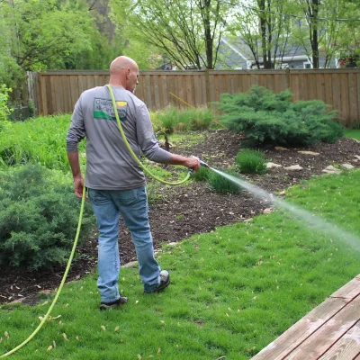 tech spraying green lawn