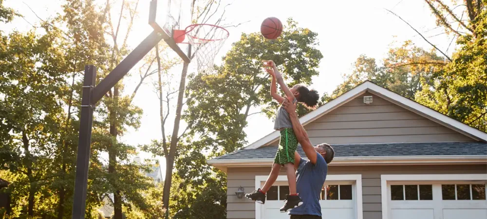 father and daughter playing basketball outside